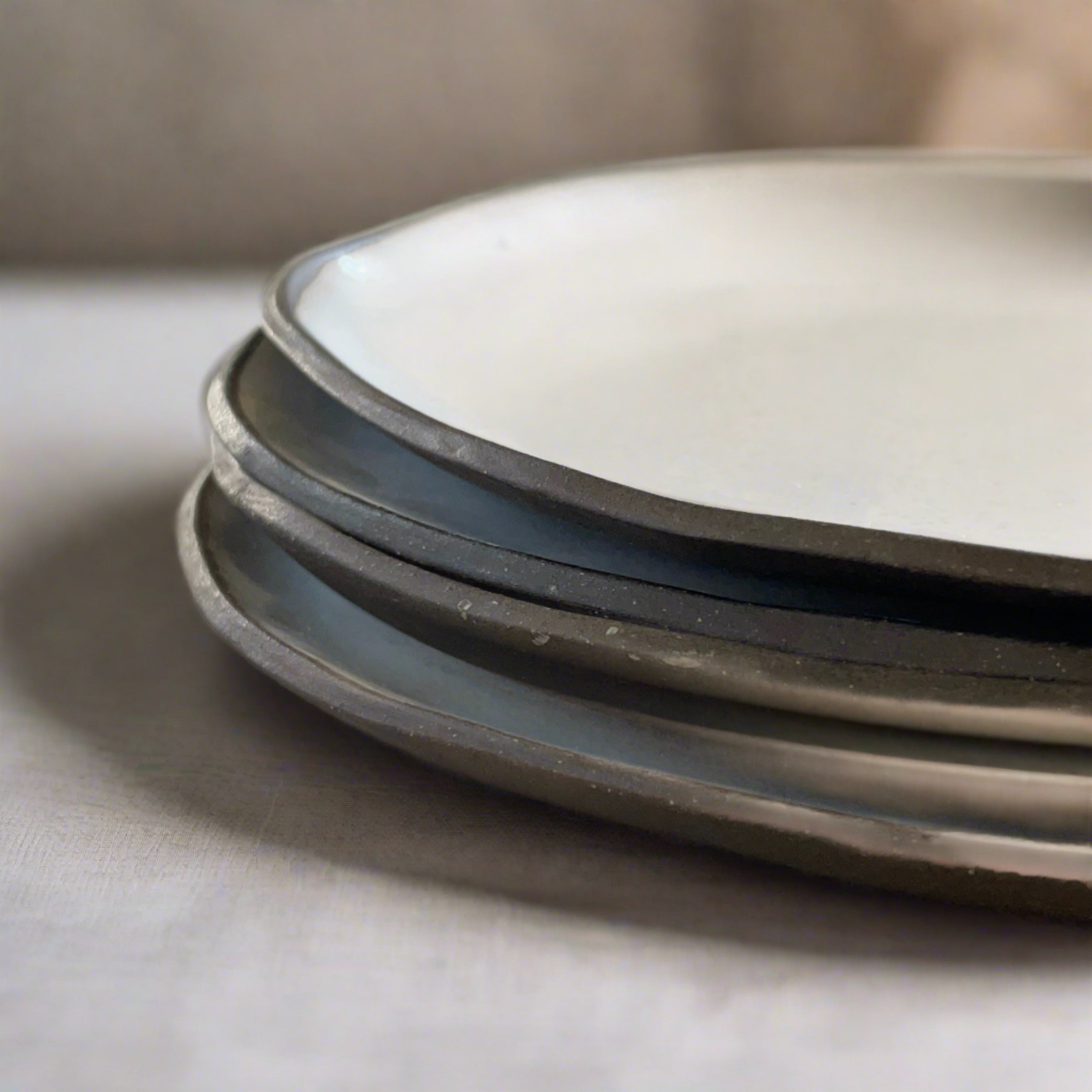 four stacked white handmade ceramic dinner plates