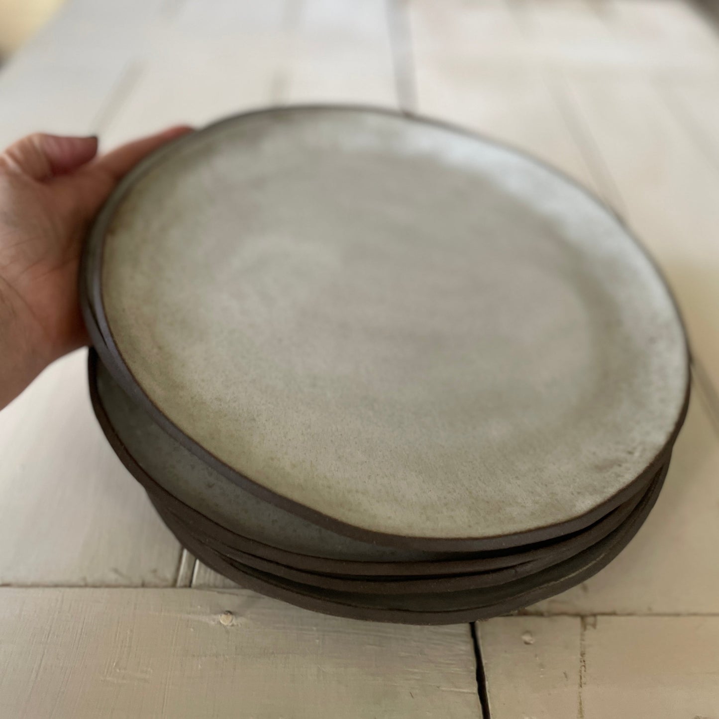 stack of four white handmade ceramic dinner plates